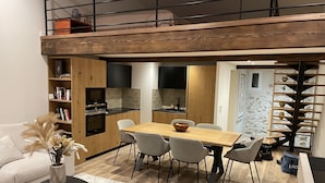 Un appartement moderne de style « loft » comprenant un espace repas, une cuisine et une chambre située en mezzanine.