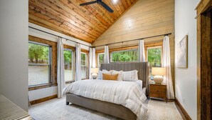 Camera da letto con un letto grande, soffitto in legno e diverse finestre.