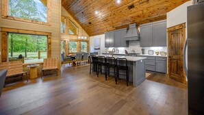 Un'ampia cucina con soffitto in legno, ampie finestre e un'isola centrale con sgabelli da bar.