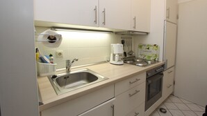 Une cuisine de taille réduite, équipée d’un évier, d’une cuisinière et d’une machine à café.