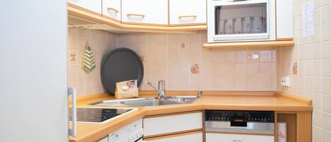 A compact kitchen with white cabinets, a built-in oven, a microwave, and a dishwasher.