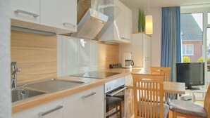 Une cuisine moderne équipée d’un four encastré, d’un évier et d’un coin repas avec une table et des chaises.