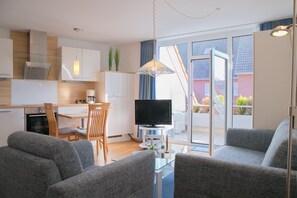 A modern living room with grey sofas, a flat-screen TV, and a glass coffee table. - House Seerose App. 5 incl. WLAN (Grömitz)