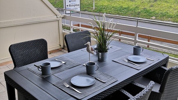 Een eettafel buiten, met uitzicht op een gazon en een hek op de achtergrond.