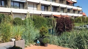 Un coin repas avec une table dressée pour deux personnes, une plante en pot et une assiette de fruits.