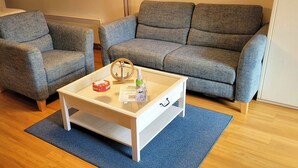 A living room with a sofa, two armchairs, a coffee table, and a small table with a glass and a bottle. - House Seerose App. 2 incl. WLAN (Grömitz)
