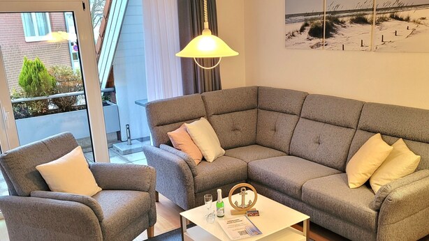 A modern living room with a grey sectional sofa, a matching armchair, and a coffee table. - House Seerose App. 7 incl. WLAN (Grömitz)