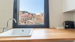 A modern kitchen with a large window, a sink, and a coffee machine. - A Casa Das Letras (Cangas)