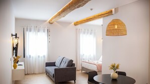 A modern living room with a sofa, a dining table with chairs, and a bed with a white headboard. - A Casa Das Letras (Cangas)