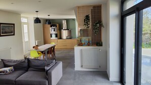 Une cuisine moderne dotée d’appareils électroménagers intégrés, un coin repas avec une table et des chaises, et une grande fenêtre offrant une vue sur l’extérieur.