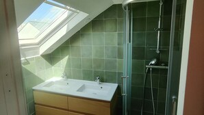 Une salle de bain dotée d’un puits de lumière, d’une douche et d’un meuble-lavabo avec des tiroirs.