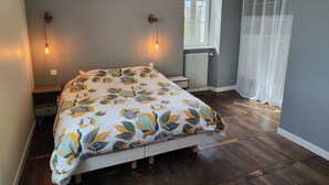 Une chambre à coucher avec un lit, deux lampes fixées au mur, une fenêtre donnant sur un paysage agréable et un radiateur.