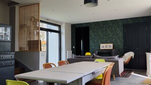 Une cuisine moderne avec un coin repas, comprenant une grande table, des chaises et des luminaires suspendus.