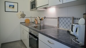 A kitchen with white cabinets, a microwave, a coffee maker, and a tiled backsplash. - House Belvedere App. 23 WLAN incl. (Grömitz)
