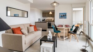 Una sala moderna con sofá, mesa de centro y comedor con sillas y una mesa.