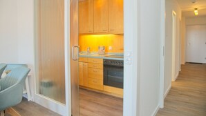 A modern kitchen with wooden cabinets, a built-in oven, and a countertop. - House Belvedere App. 44 WiFi incl. (Grömitz)