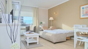 A modern, well-lit room with a bed, a white table, and a chair. - Hanseat II App. 137 (Grömitz)
