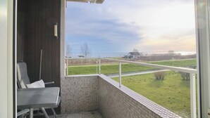A balcony with a view of a grassy area and a body of water. - Hanseat II App. 137 (Grömitz)