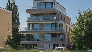 Um edifício residencial com vários andares, varandas, janelas amplas e fachada de tijolos.