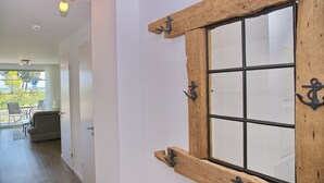 Quarto com janela de madeira com ganchos de metal, um sofá e um espaço de refeições com cadeiras.