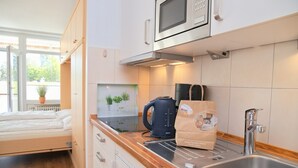 Une petite cuisine équipée d’un four à micro-ondes, d’une bouilloire et d’un sac de provisions.