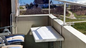 A balcony with a view of the sea, a white van, and a grassy area. - Hanseat I Appartement. 82 (Grömitz)