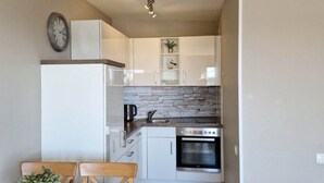 A compact kitchen with white cabinets, a built-in oven, and a coffee maker. - Hanseat I Appartement. 82 (Grömitz)