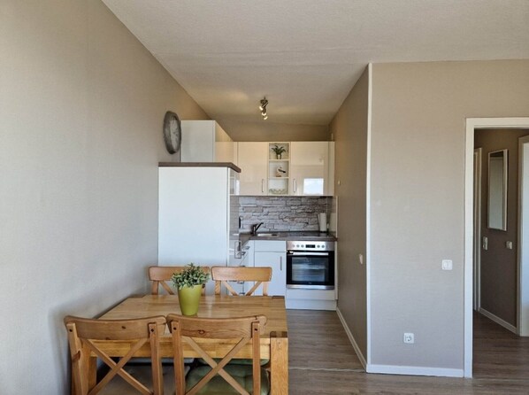 A compact kitchen with white cabinets, a built-in oven, and a stone backsplash. - Hanseat I Appartement. 82 (Grömitz)