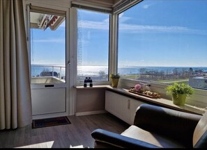 A room with a view of the sea, a radiator, a chair, and a window with a curtain. - Hanseat I Appartement. 82 (Grömitz)