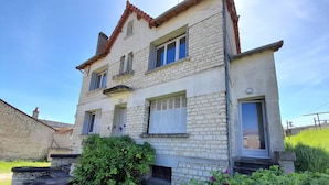 A two-story stone house with a balcony, a small garden, and a stone staircase leading to the entrance. - Charming T3 in La Roche-Posay Center with Garden, Garage, and Modern Amenities (La Roche-Posay)