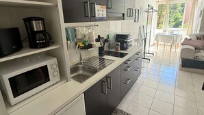 Moderni keittiö, jossa on mikroaaltouuni, kahvinkeitin ja pesuallas.