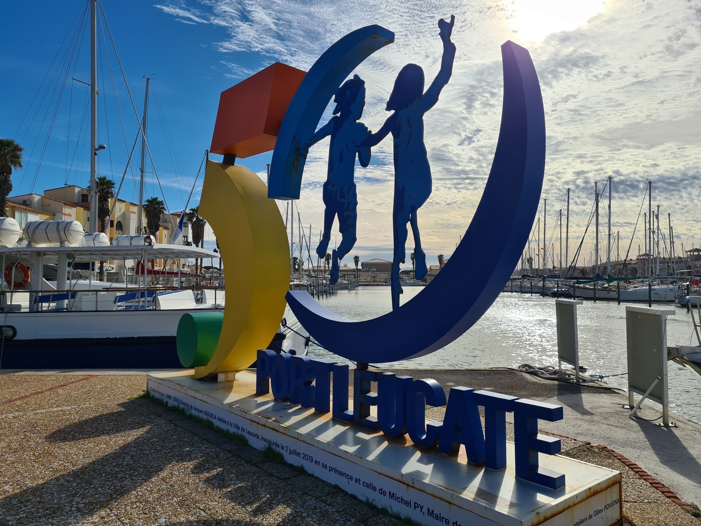 A large outdoor sculpture with the word "POURTE" and a child holding hands with an adult.
