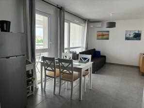 Uma sala de estar moderna com área de jantar, janelas amplas e vista para o exterior.