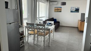 Une cuisine moderne équipée d’un réfrigérateur, d’une table à manger avec des chaises et d’un canapé dans l’espace salon.
