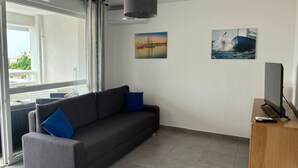 Un salon moderne avec un canapé, un téléviseur à écran plat et des œuvres d’art accrochées aux murs.