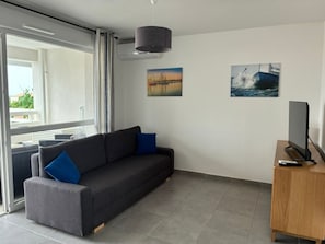 A modern living room with a sofa, a flat-screen TV, and artwork on the walls.