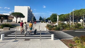 Un passage piéton protégé par des bollards, un ciel dégagé et un bâtiment en arrière-plan.