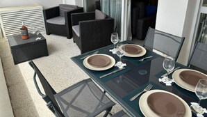 Un coin repas avec une table dressée pour quatre personnes, comprenant des assiettes, des couverts et des verres.
