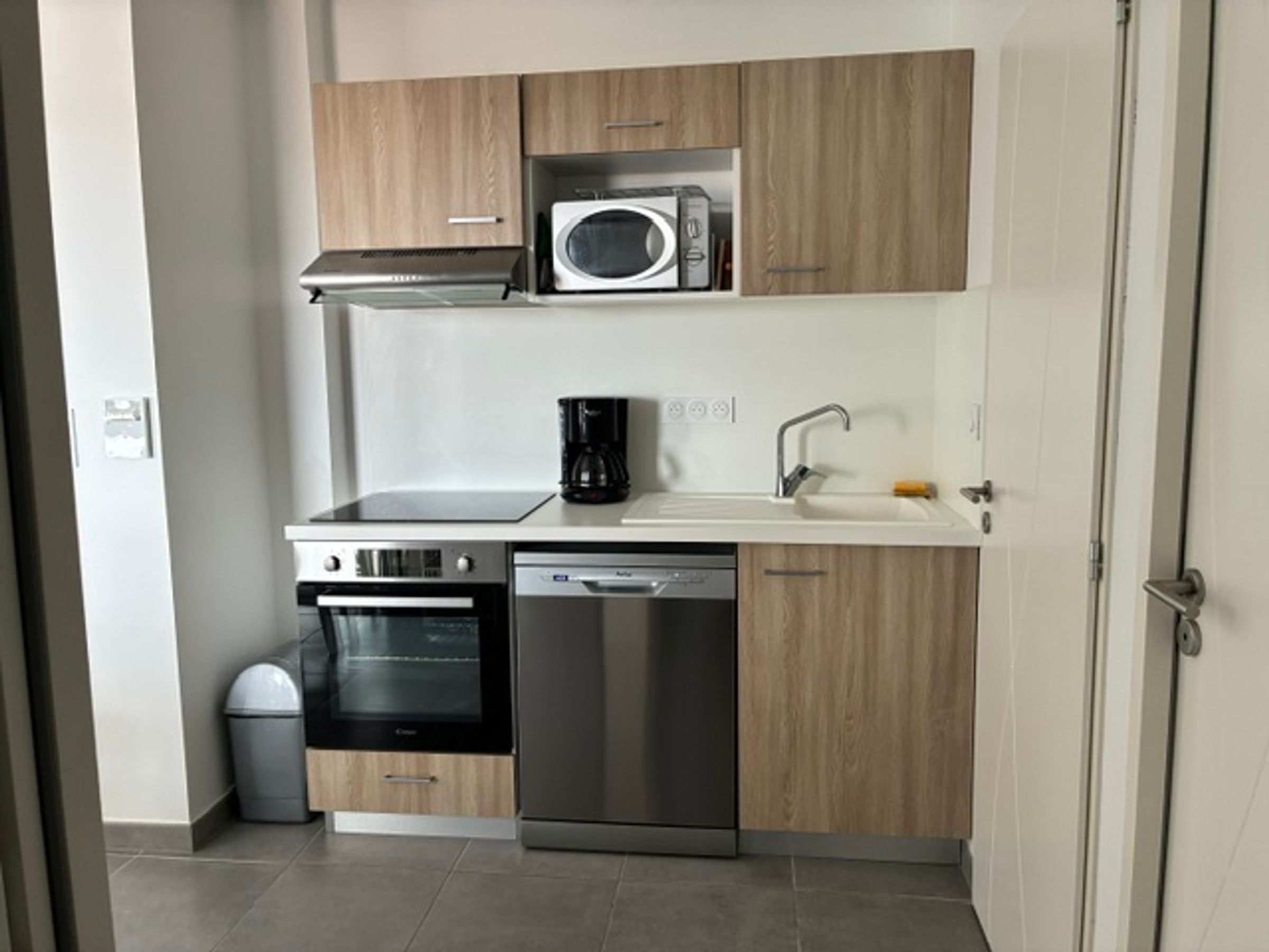Una cocina compacta equipada con microondas, cafetera, horno y lavavajillas.