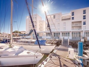 Moored sailboats and yachts line the wooden pier, offering a serene waterfront view of the surrounding cityscape.