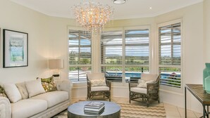 A spacious living room with a large window, a chandelier, and a pool view. - Cullengetty Estate!! (Berry)