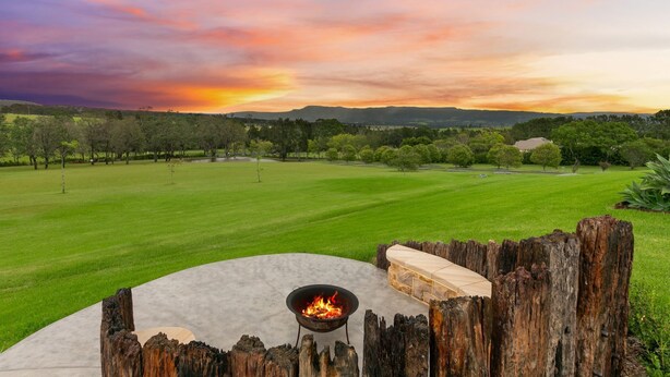 A fire pit with a view of a grassy field and distant mountains during sunset. - Cullengetty Estate!! (Berry)