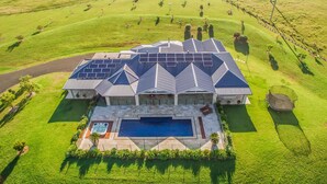 A large house with a swimming pool, surrounded by a well-maintained lawn and solar panels on the roof. - Cullengetty Estate!! (Berry)