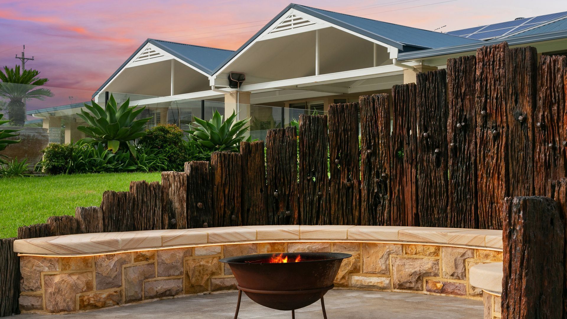 A modern house with a stone fire pit in the backyard.