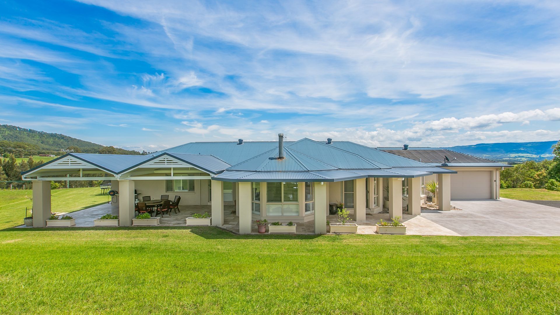 Una casa moderna con un porche cubierto, un garaje y vistas del paisaje circundante.