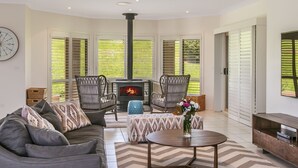 A cozy living room with a fireplace, comfortable seating, and a large window with blinds. - Cullengetty Estate!! (Berry)