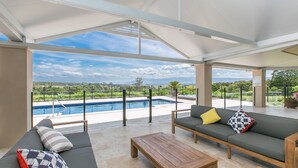 A modern outdoor living area with a pool, a sofa, and a wooden table. - Cullengetty Estate!! (Berry)