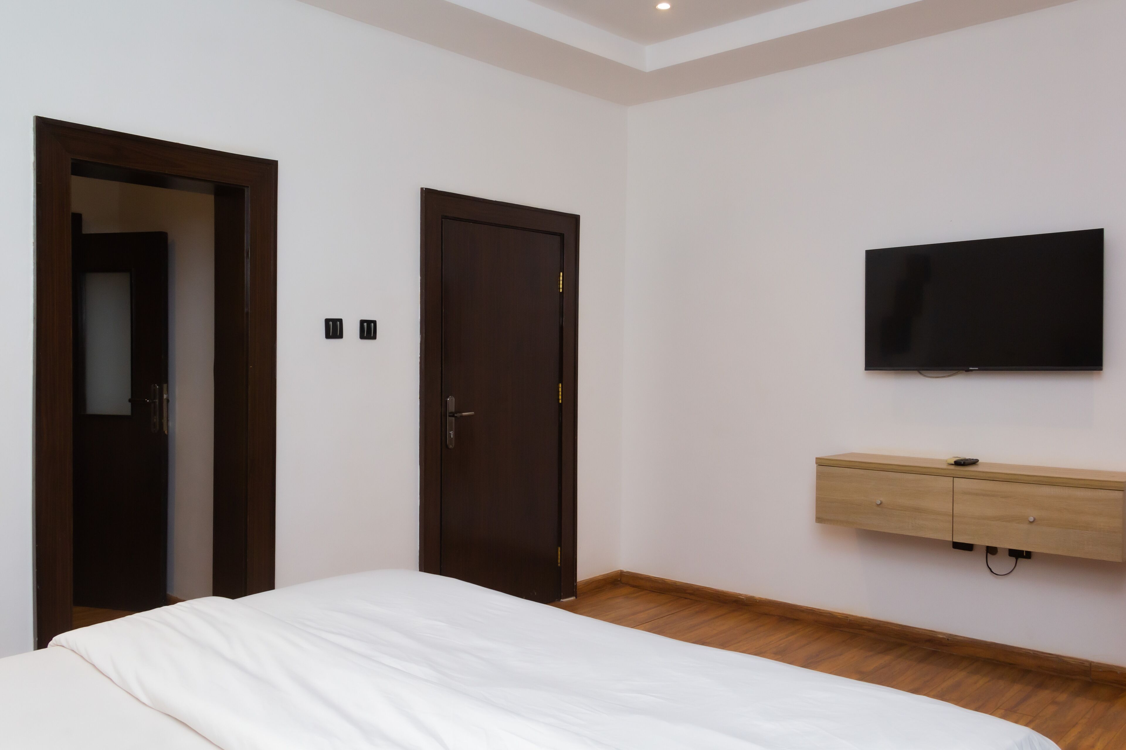 A bedroom with a bed, a wardrobe, a television, and a door.