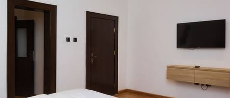 A bedroom with a bed, a wardrobe, a television, and a door.