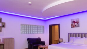 Une chambre d’hôtel moderne comprenant un lit, une petite table, un canapé en cuir et un meuble.